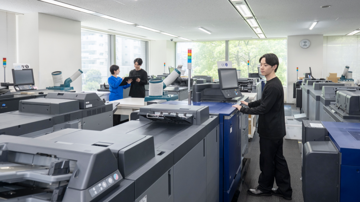 An employee at work in a room lined with production printers