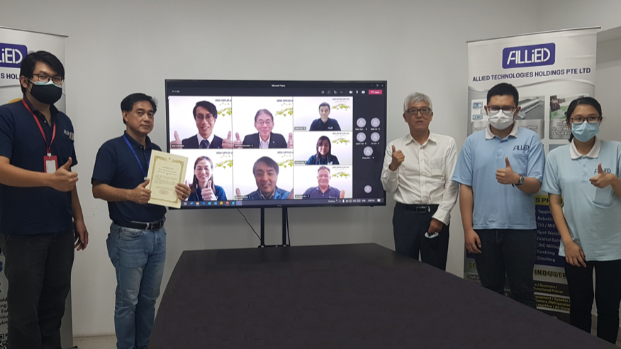 A commemorative photograph with the certificate, taken in a meeting room with online participants