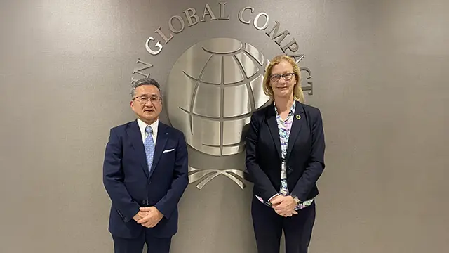 Toshimitsu Taiko, President and CEO of Konica Minolta (left), and Sue Allchurch of the United Nations Global Compact (right), standing in front of the UN Global Compact logo