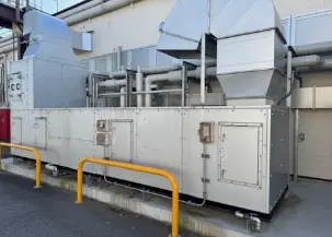 工場の屋外に設置された、ダクトが並ぶ大型の空調設備の写真