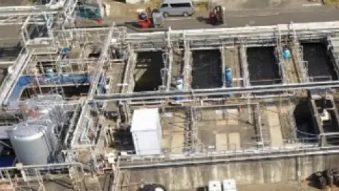 複数の処理槽と配管が並ぶ排水処理場を上空から見た写真