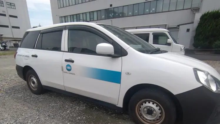 コニカミノルタのロゴを入れた白い営業車を側面から見た写真