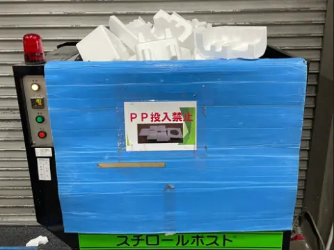 物流倉庫に設置された発泡スチロール減容機に、回収した使用済み発泡スチロールが投入されている写真