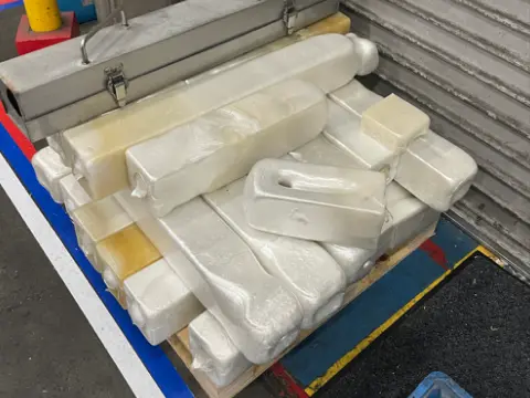 減容機で圧縮され、棒状の塊になった発泡スチロールがパレットに積み上げられている写真